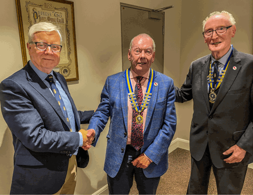 Mr Brian Duffy MBE, left, congratulates Mr Paul Stephenson on becoming District Chairman while Lt Col Ken Martin observes.