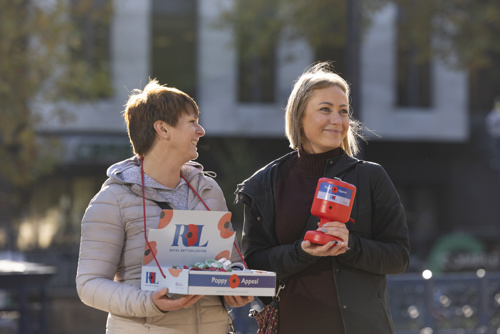 Two female poppy appeal collectors stood outside with a collecting tin and box of poppies